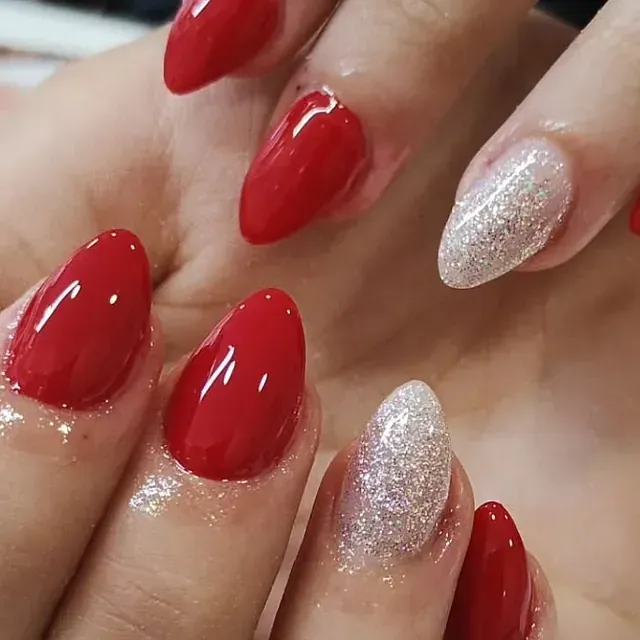Un primer plano de la mano de una mujer con uñas rojas y plateadas.