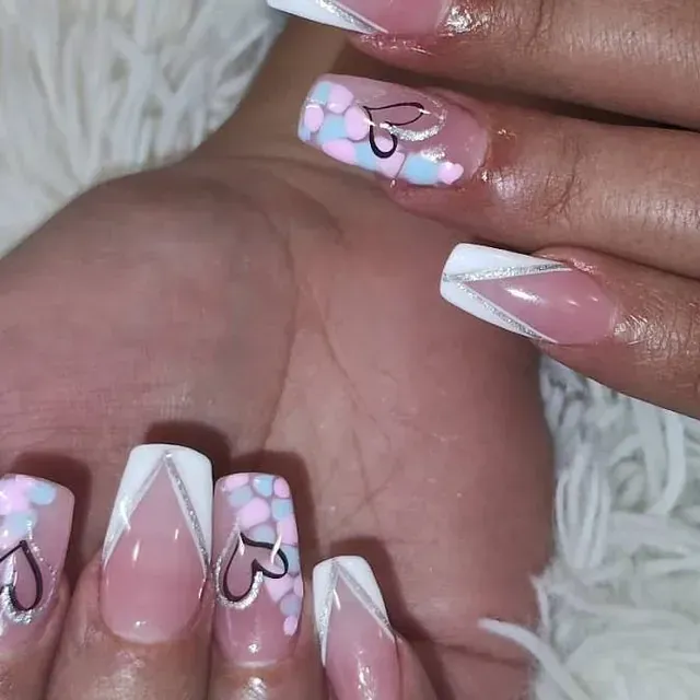 Un primer plano de las uñas de una mujer con corazones en ellas.