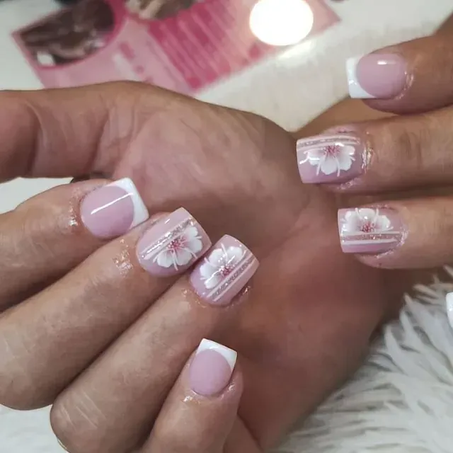 Un primer plano de las uñas de una mujer con flores en ellas.