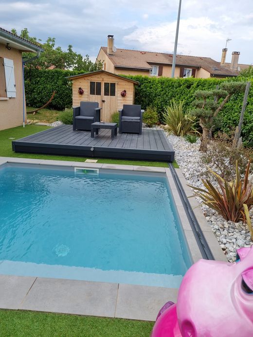 Piscine dans la cour arrière avec chaises longues, petit abri de jardin et haies sous un ciel nuageux