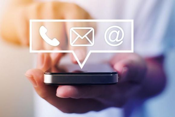 Una persona sostiene un teléfono celular con un ícono de contáctenos.