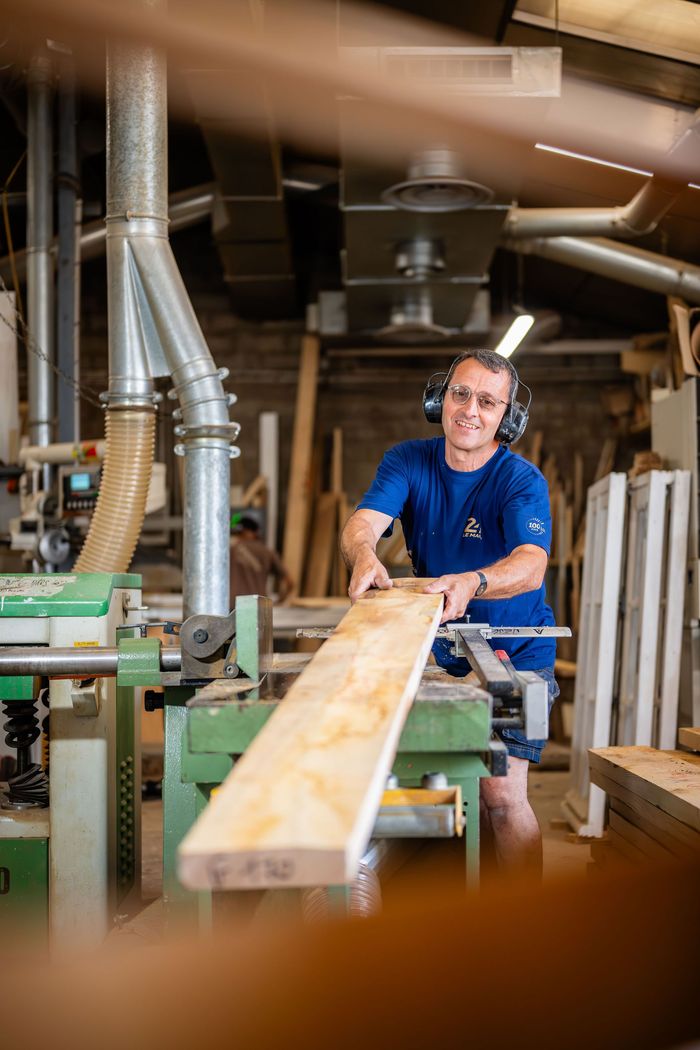 Ouvrier souriant avec une planche de bois entre les mains