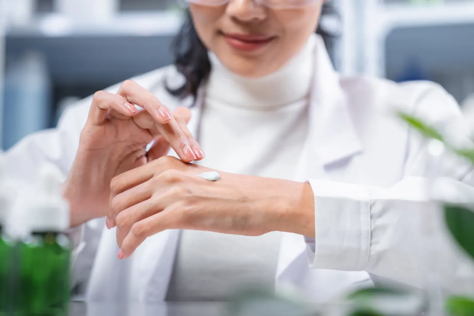 Ein Wissenschaftler im weißen Laborkittel untersucht sorgfältig eine Handprobe in einem hellen Labor.