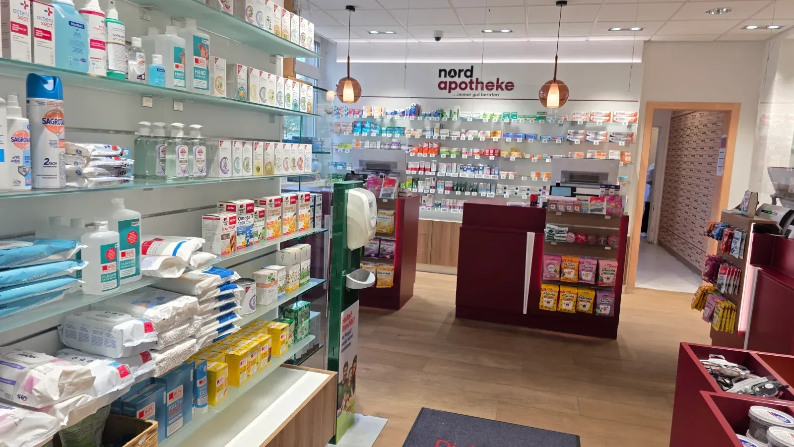 Apothekenregal mit Medikamenten und Toilettenartikeln, gesehen vom Verkaufsschalter aus.