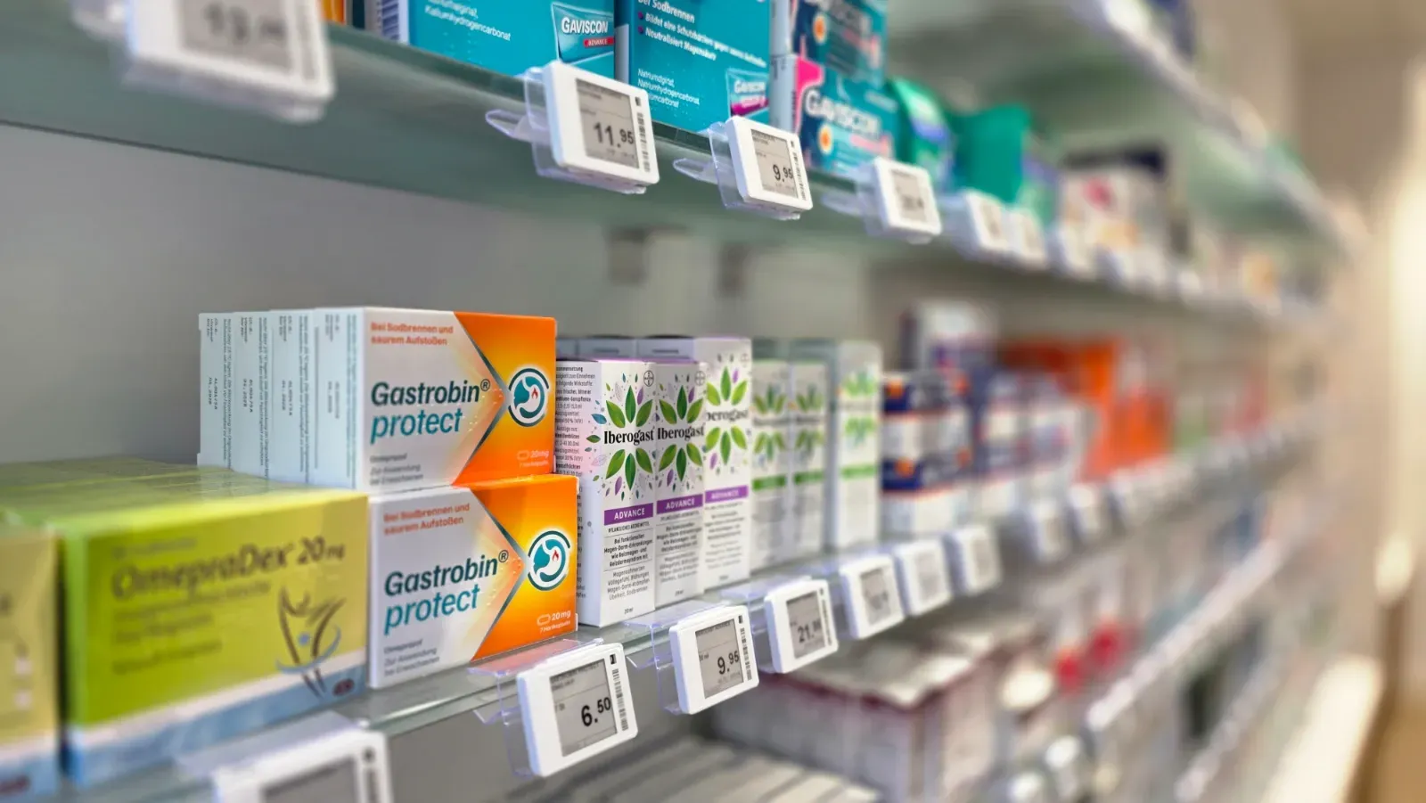 Apothekenregal mit in Reihen angeordneten, verpackten Erkältungs- und Allergiepräparaten, Preisschilder darunter.