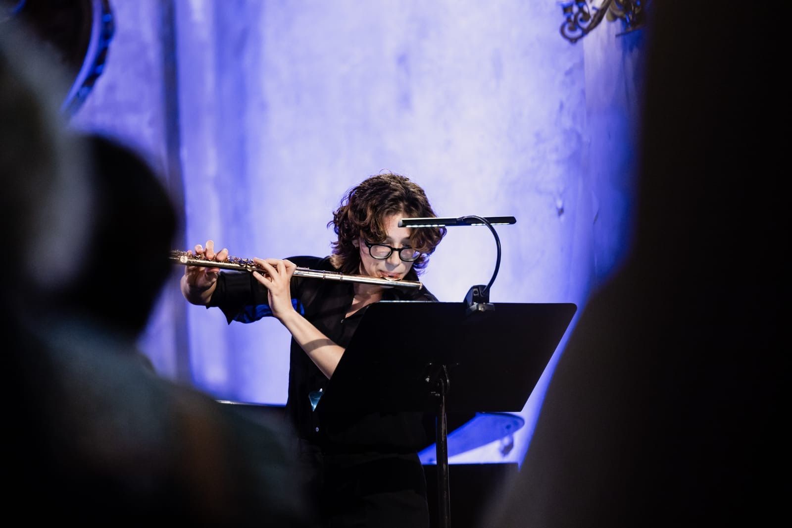 Eine Person, die in einem Orchester Geige spielt, von der Seite gesehen.