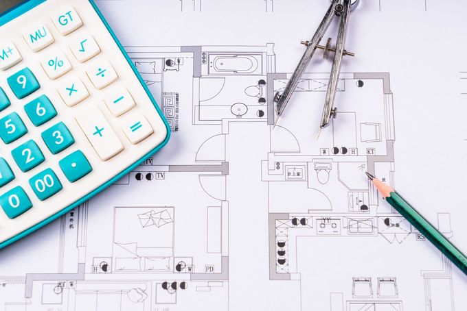 Une maison en bois neuve, avec des panneaux solaires sur un toit de tuiles, entourée de terre nue par temps nuageux.