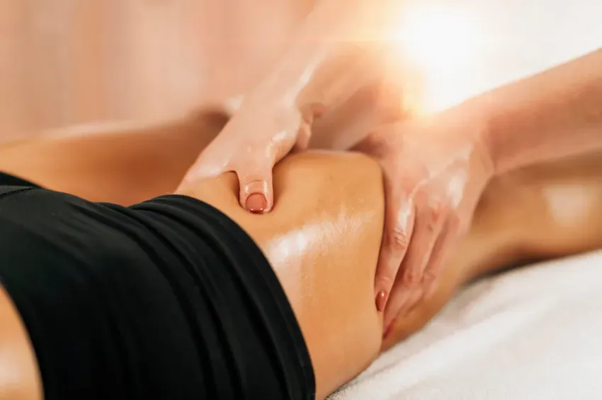 Manos masajeando la parte baja de la espalda de una persona durante un tratamiento de spa.