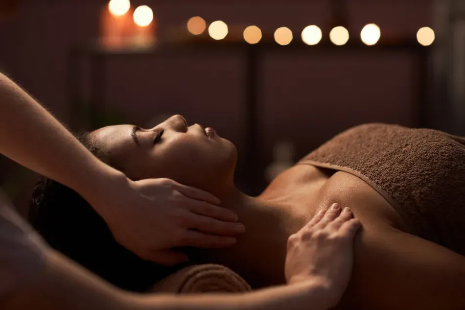 Persona recibiendo un relajante masaje de cuello y hombros a la luz de las velas.