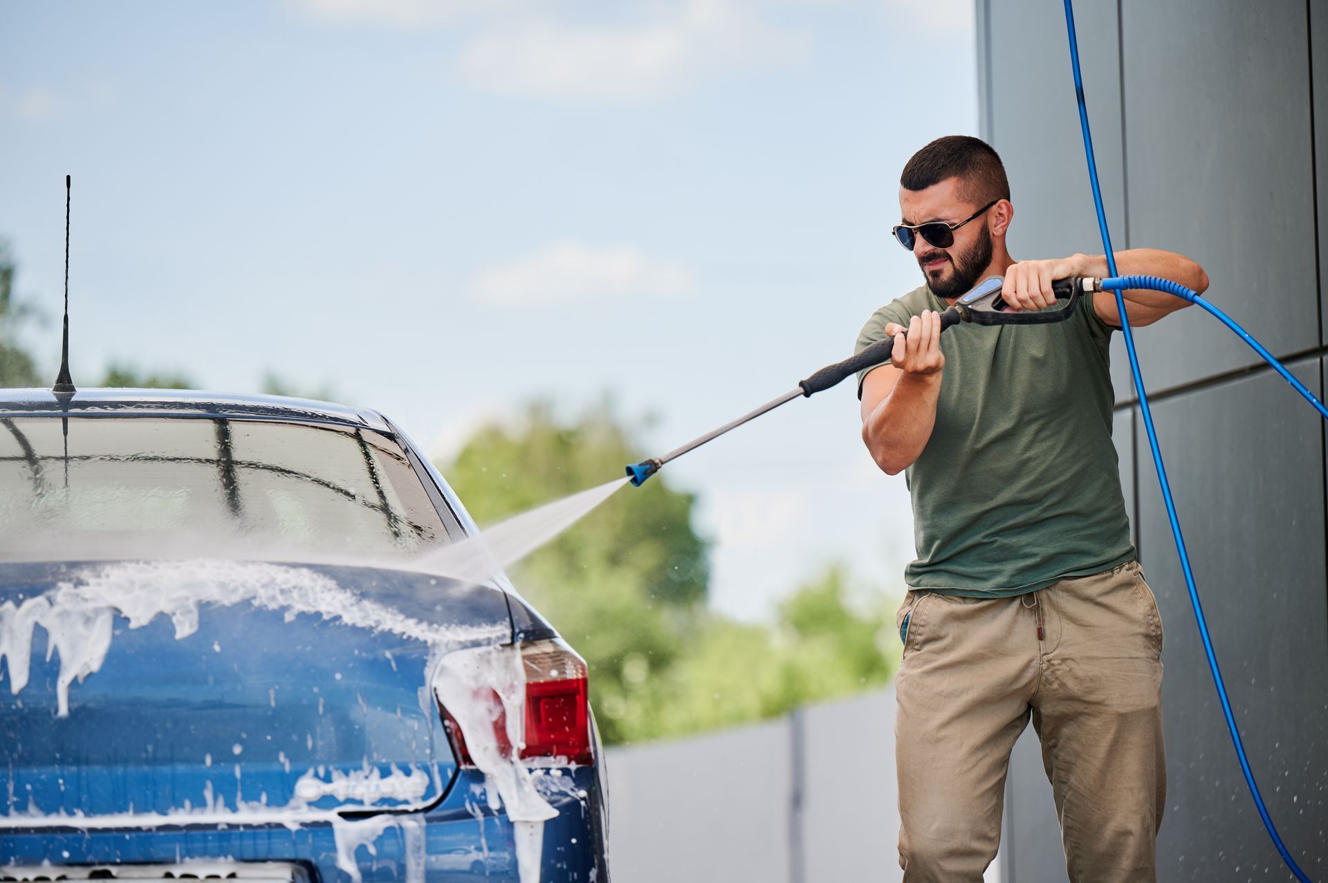Homme qui lave sa voiture au jet à haute pression
