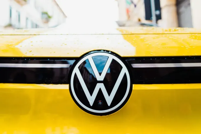 Primer plano del logotipo circular de Volkswagen en la parte delantera de un vehículo amarillo brillante.