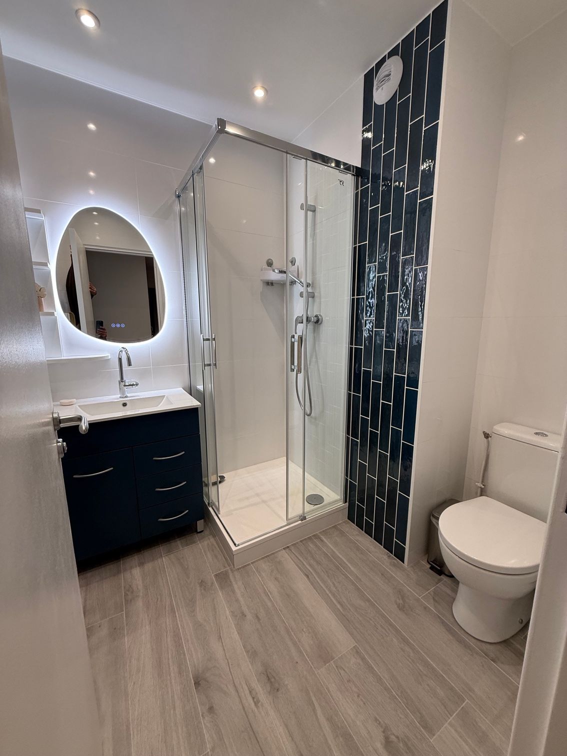Salle de bains moderne blanche avec douche, meuble-lavabo, miroir et toilettes