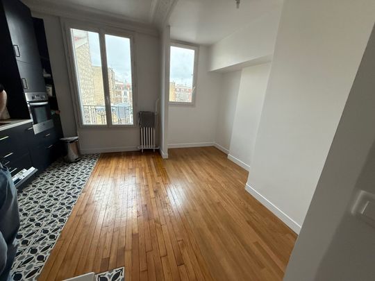 Pièce vide avec parquet, grandes fenêtres et tapis à motifs près d'un meuble TV noir