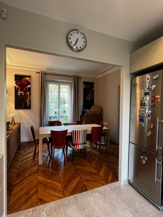 Salle à manger vue à travers une arche, avec une table en bois, des chaises rouges