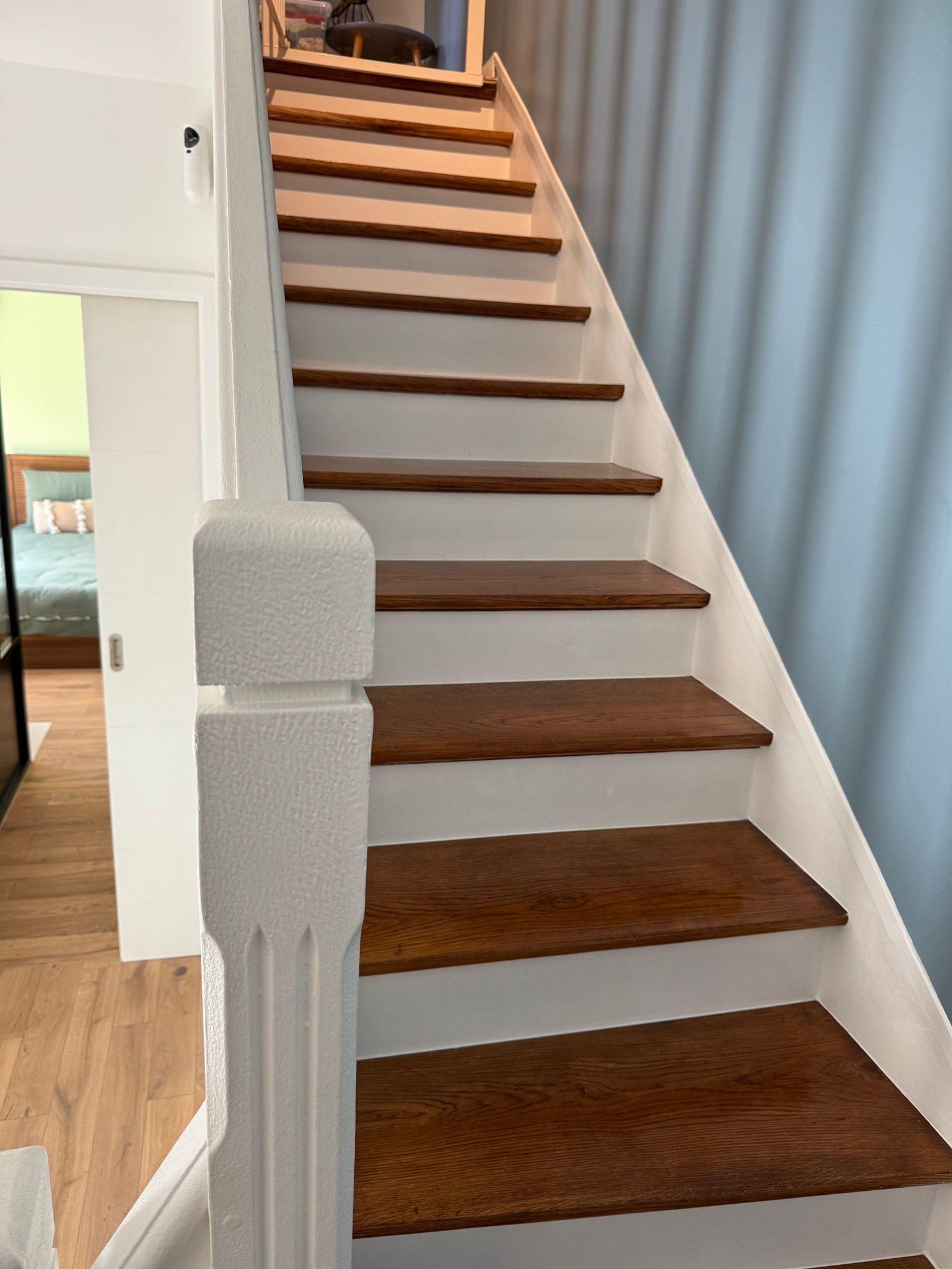 Escalier intérieur avec contremarches blanches, marches marron et mur bleu clair.