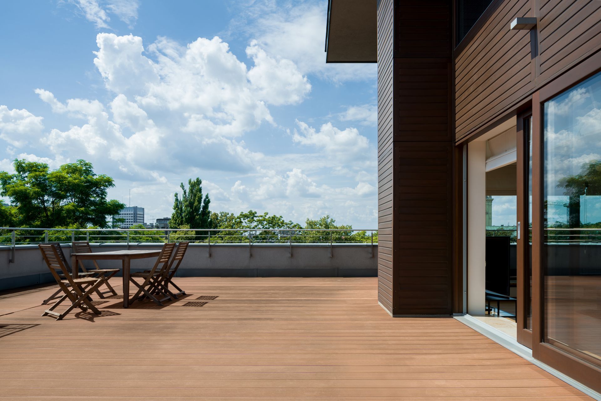 Terrasse en bois sur le toit avec table et chaises, portes vitrées.
