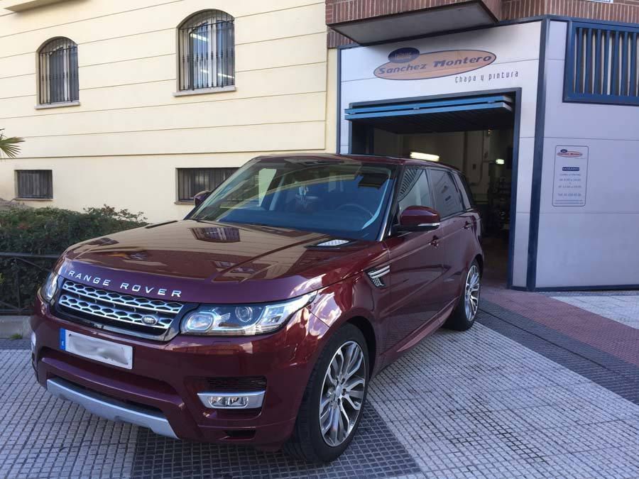 Un Range Rover rojo está estacionado frente a un edificio.