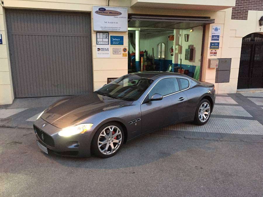 Un coche deportivo gris está aparcado delante de un garaje.