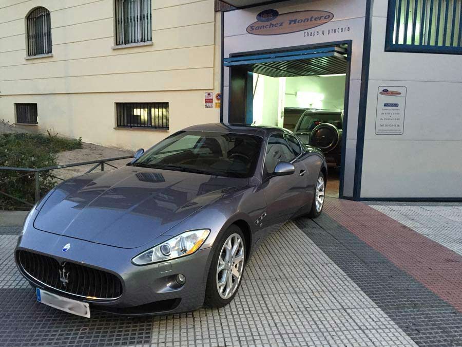 Un Maserati gris está estacionado frente a un edificio.