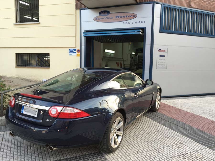 Un coche deportivo azul está aparcado delante de un edificio.