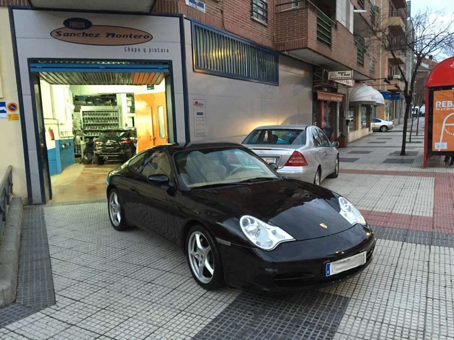 Un coche negro está aparcado delante de un garaje.