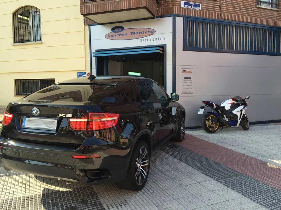 Un coche negro está aparcado delante de un edificio con una motocicleta estacionada delante de él.