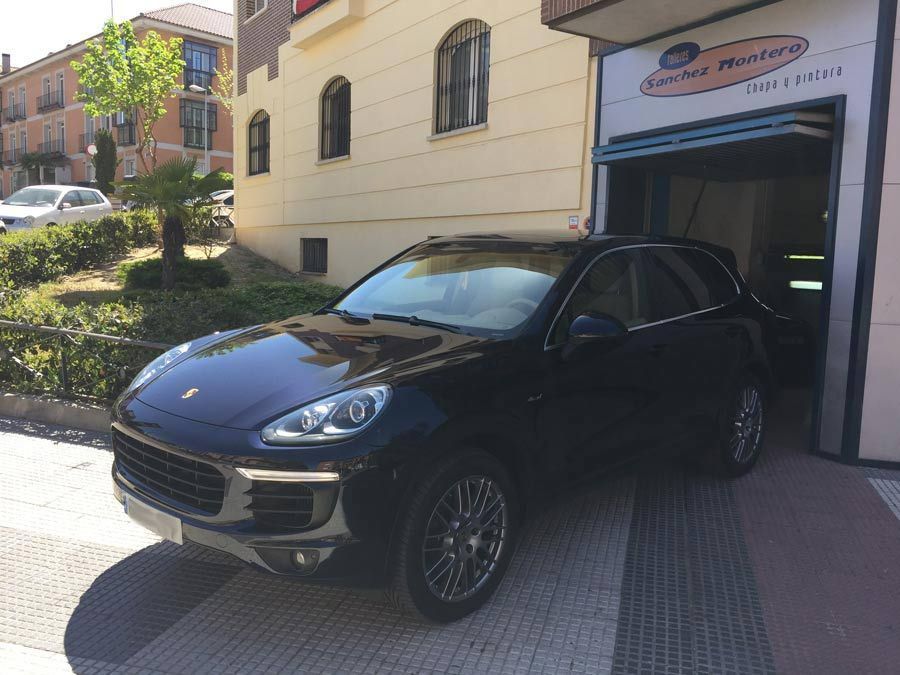 Un Porsche Cayenne negro está estacionado frente a un edificio.