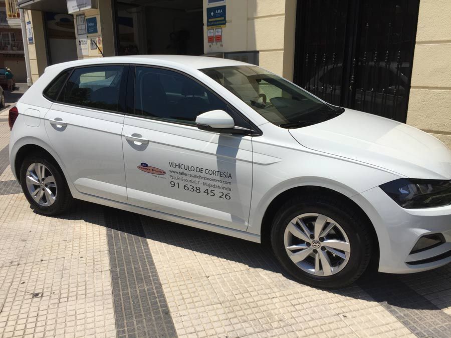 Un coche blanco está aparcado en una acera delante de un edificio.