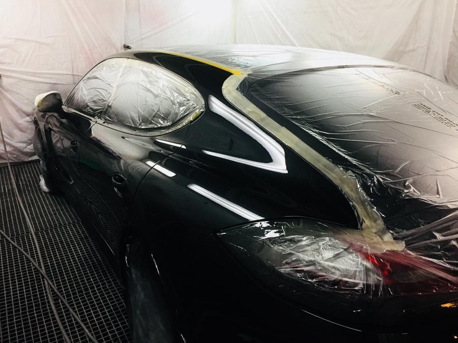 Un coche negro está siendo pintado en una cabina de pintura.