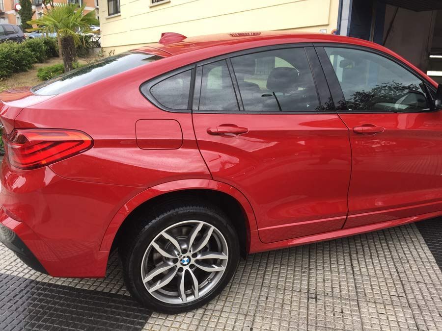 Un BMW X4 rojo está estacionado frente a un edificio.