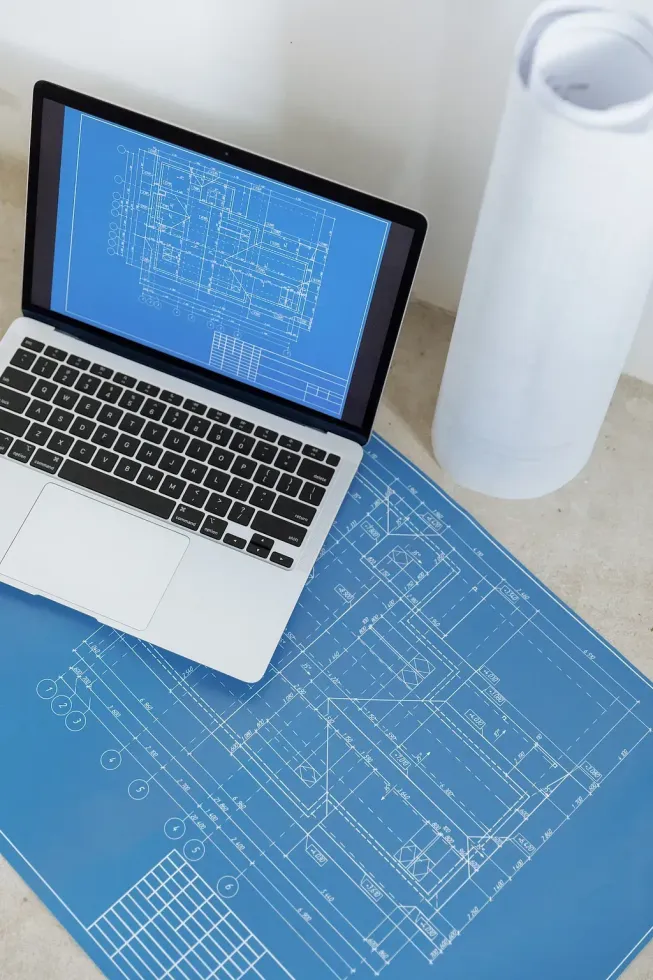 Una computadora portátil está encima de un plano en un escritorio.