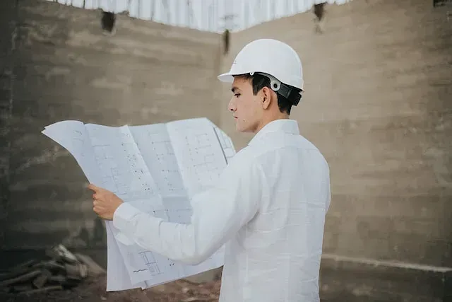 Un hombre con un casco blanco está mirando un plano.