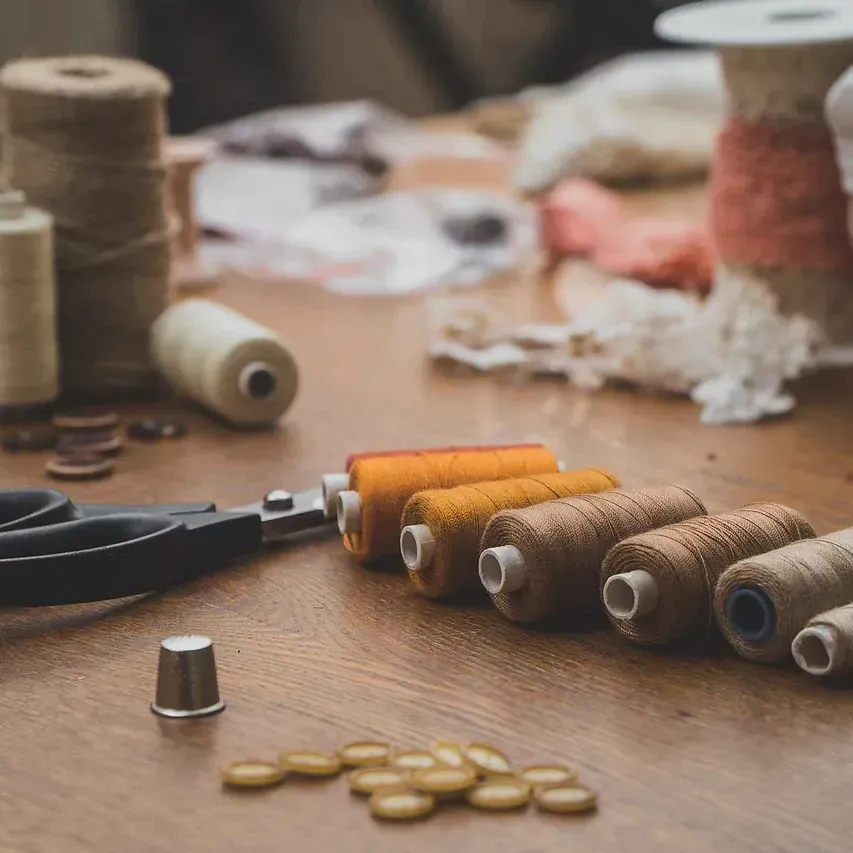 Una mesa de madera cubierta con carretes de hilo y tijeras.
