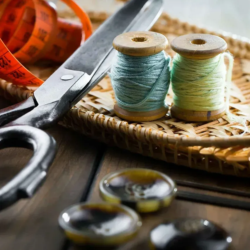 Un par de tijeras junto a dos carretes de hilo.