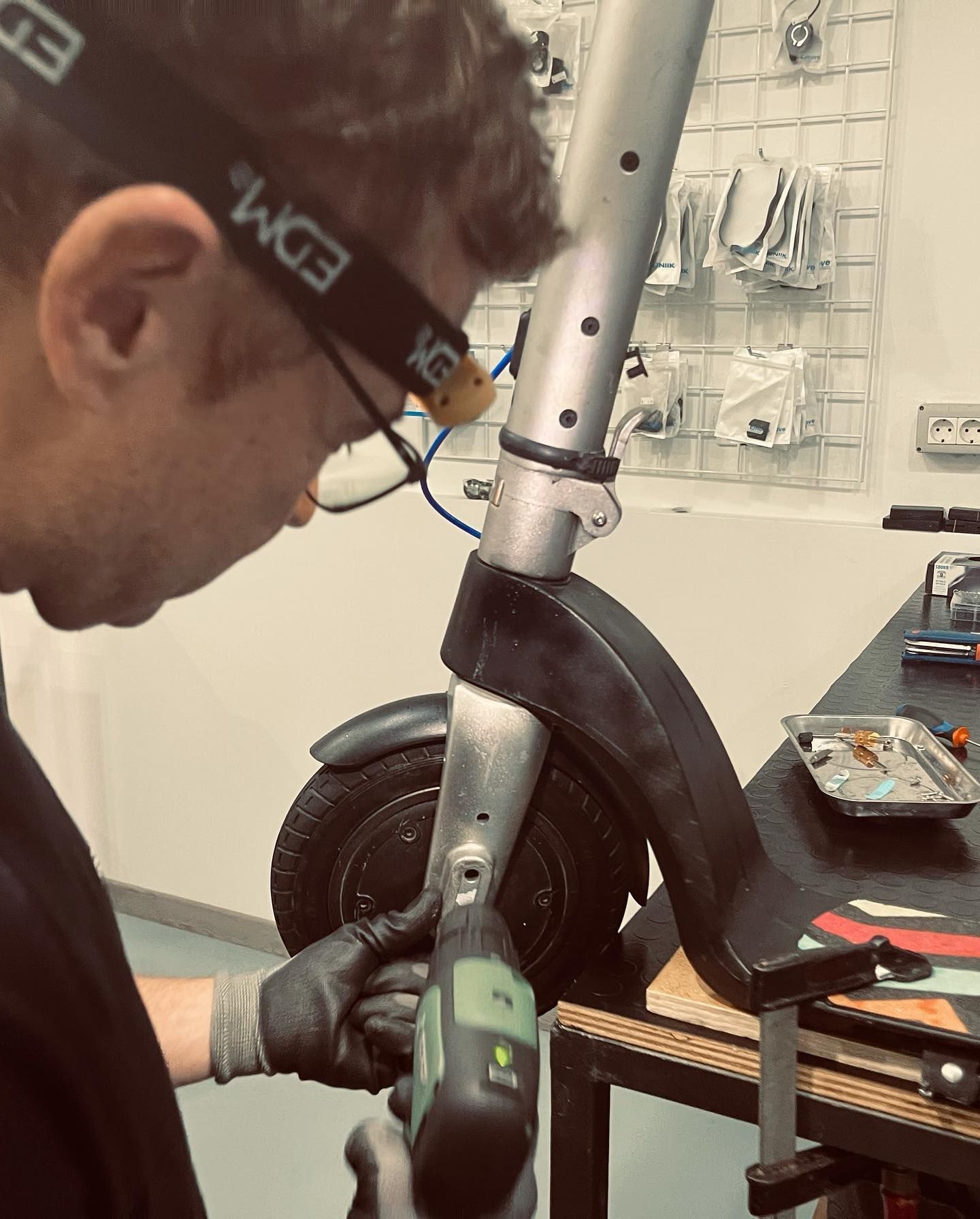 Un hombre que lleva una diadema que dice EDM está trabajando en un scooter eléctrico.