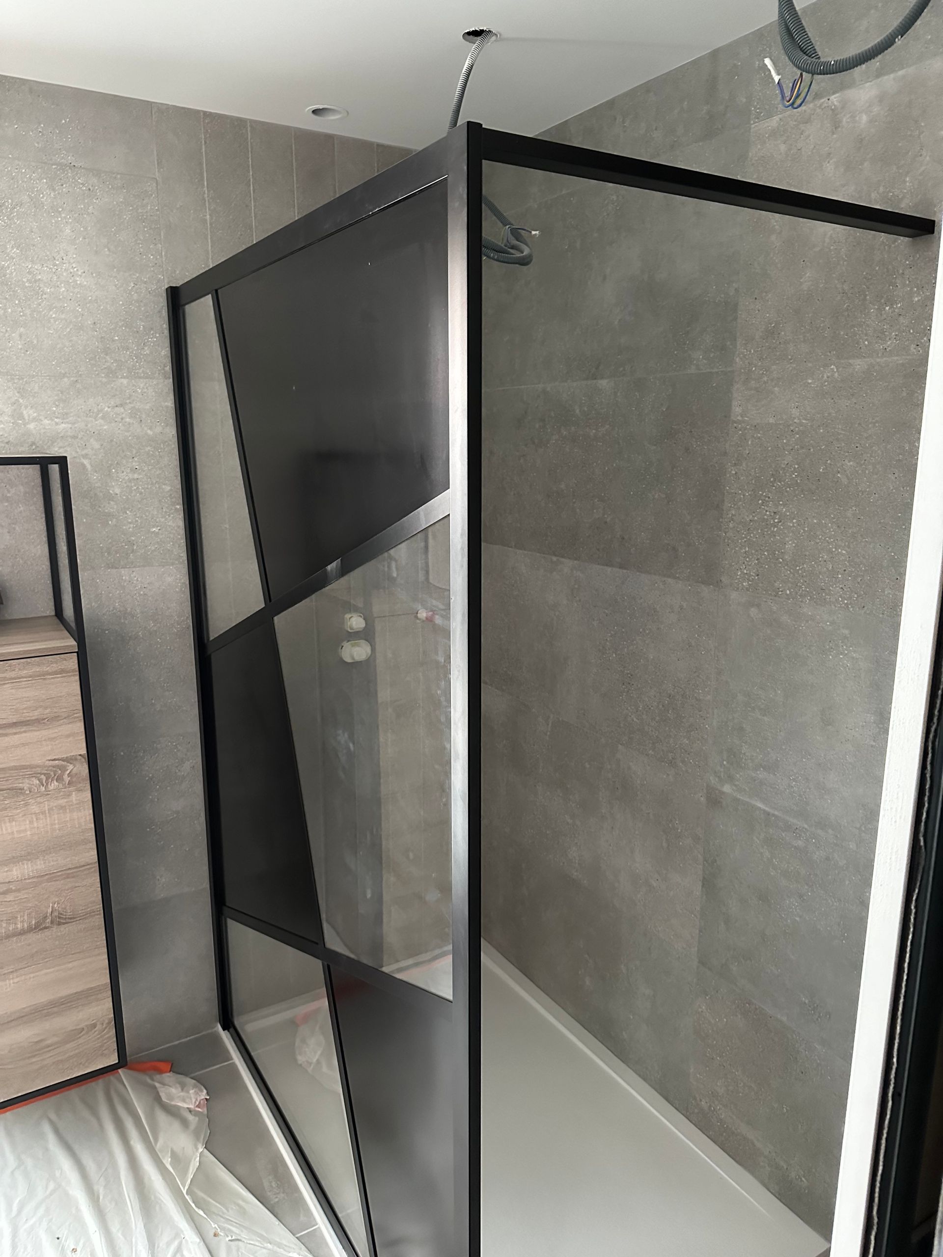 Armoire ou meuble en maille noire dans un coin de la chambre, à côté du lit et de la commode.
