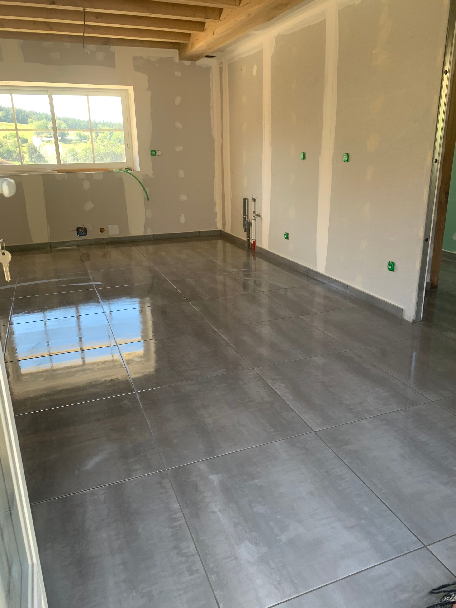 Pièce vide avec un mur d'accent turquoise, un parquet clair et des murs blancs ; pot de peinture près du côté gauche.