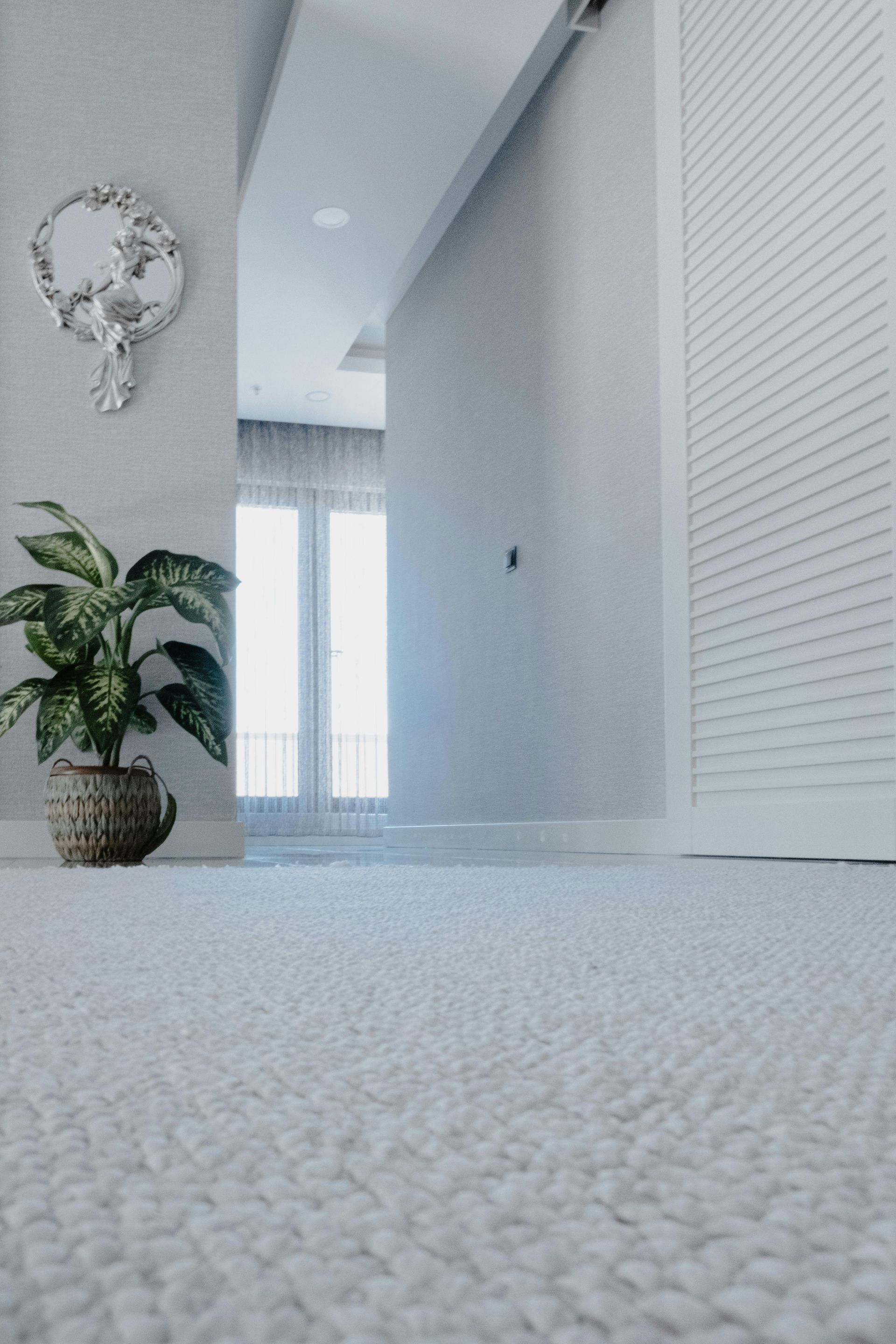 Coin vide d'une pièce avec parquet clair à chevrons et murs blancs.