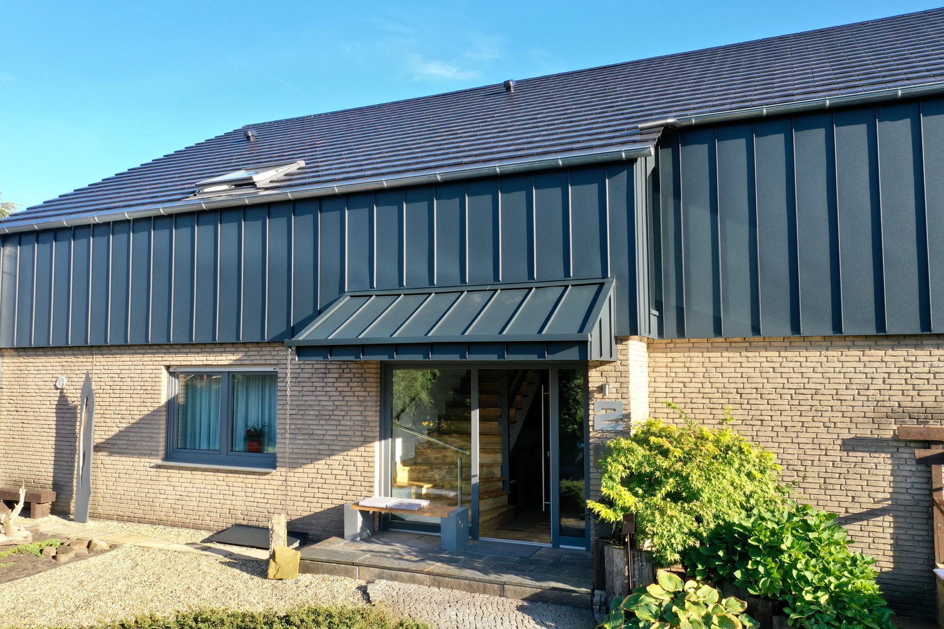 Ein rustikales Backsteingebäude mit einem Obergeschoss und Dach aus dunklem Stehfalzmetall