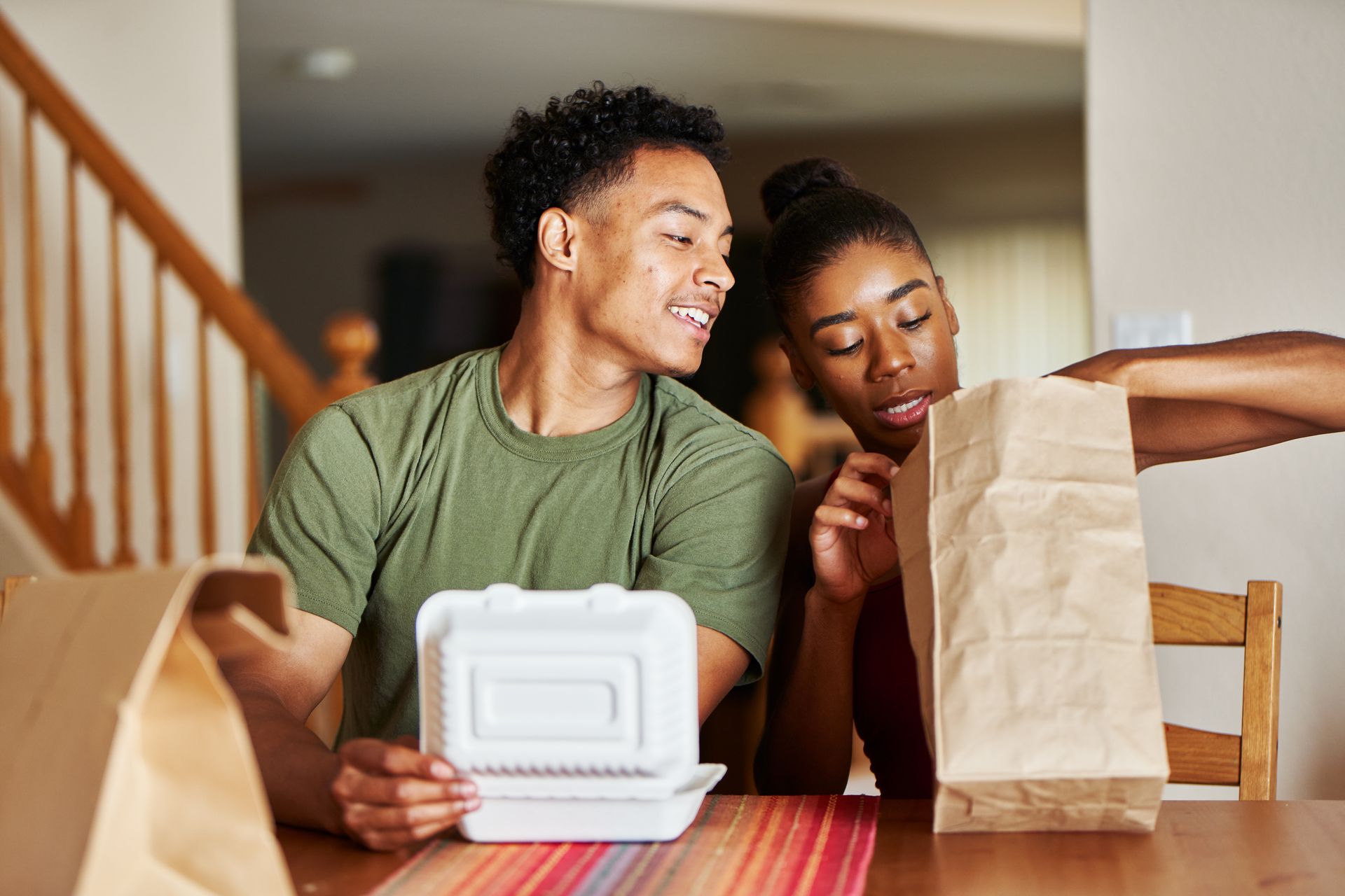Un couple examine des sacs de plats à emporter à table.