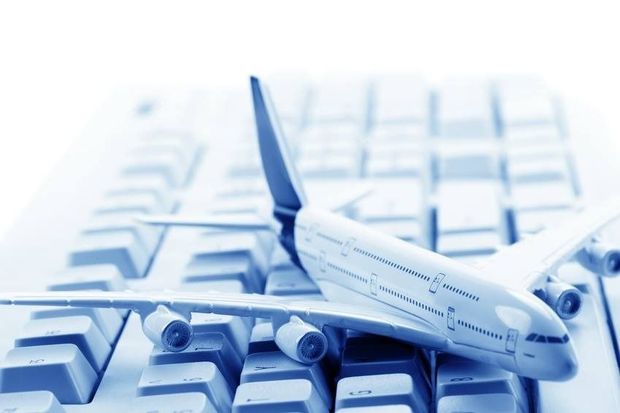 Avión de juguete sobre un teclado de ordenador, símbolo de reserva de viajes online. Tonos azules.