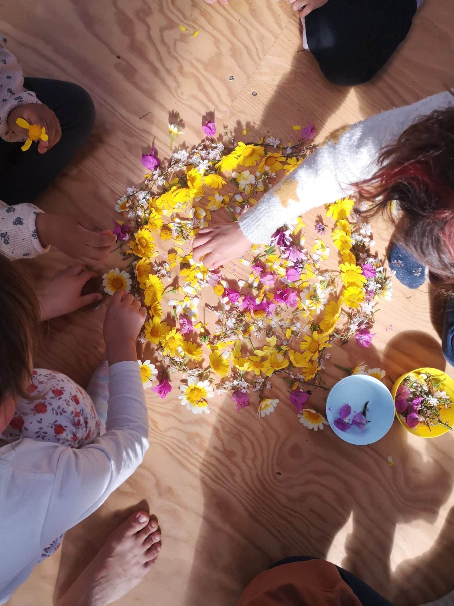 Un conjunto de jóvenes jugando con un mandala de flores en el suelo