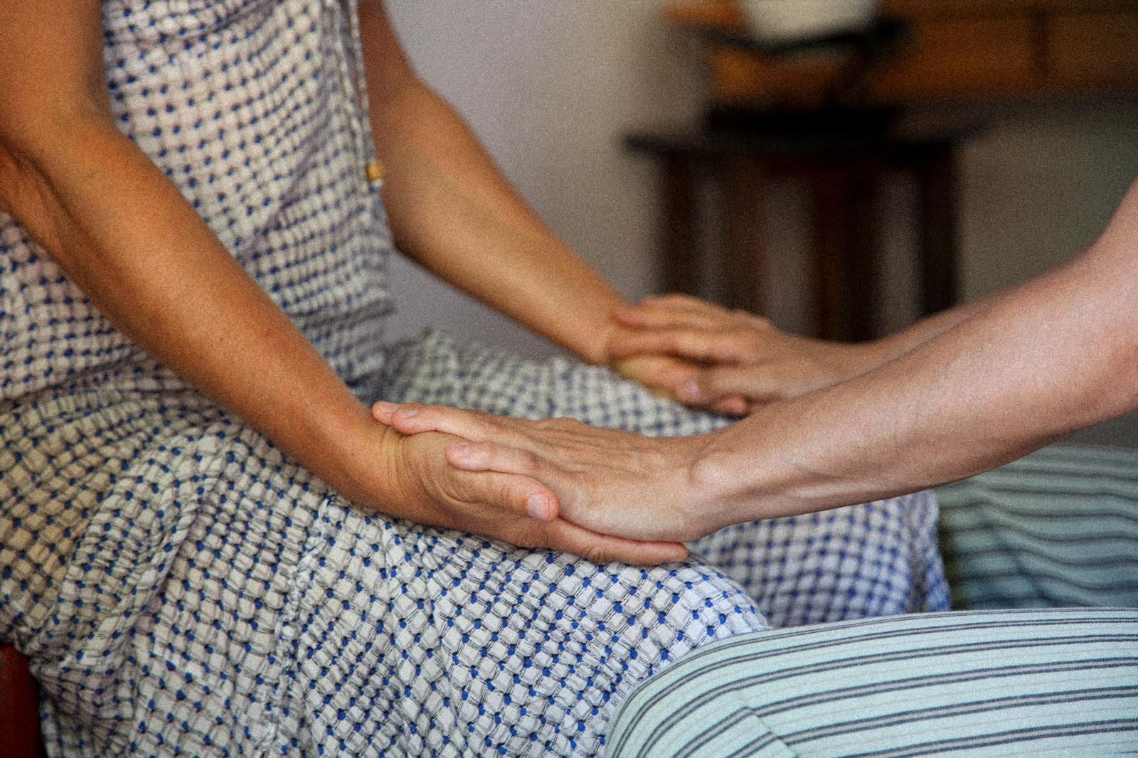 Dos personas se toman de la mano mientras están sentadas en una cama.