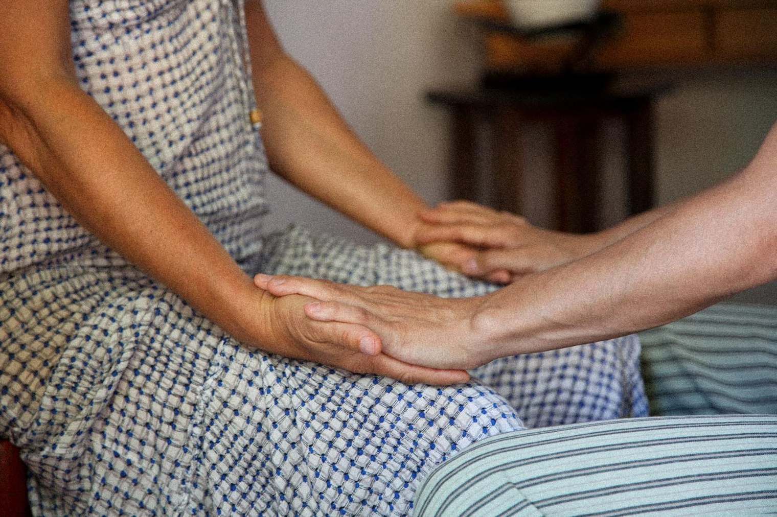 Dos personas se toman de la mano mientras están sentadas en una cama.