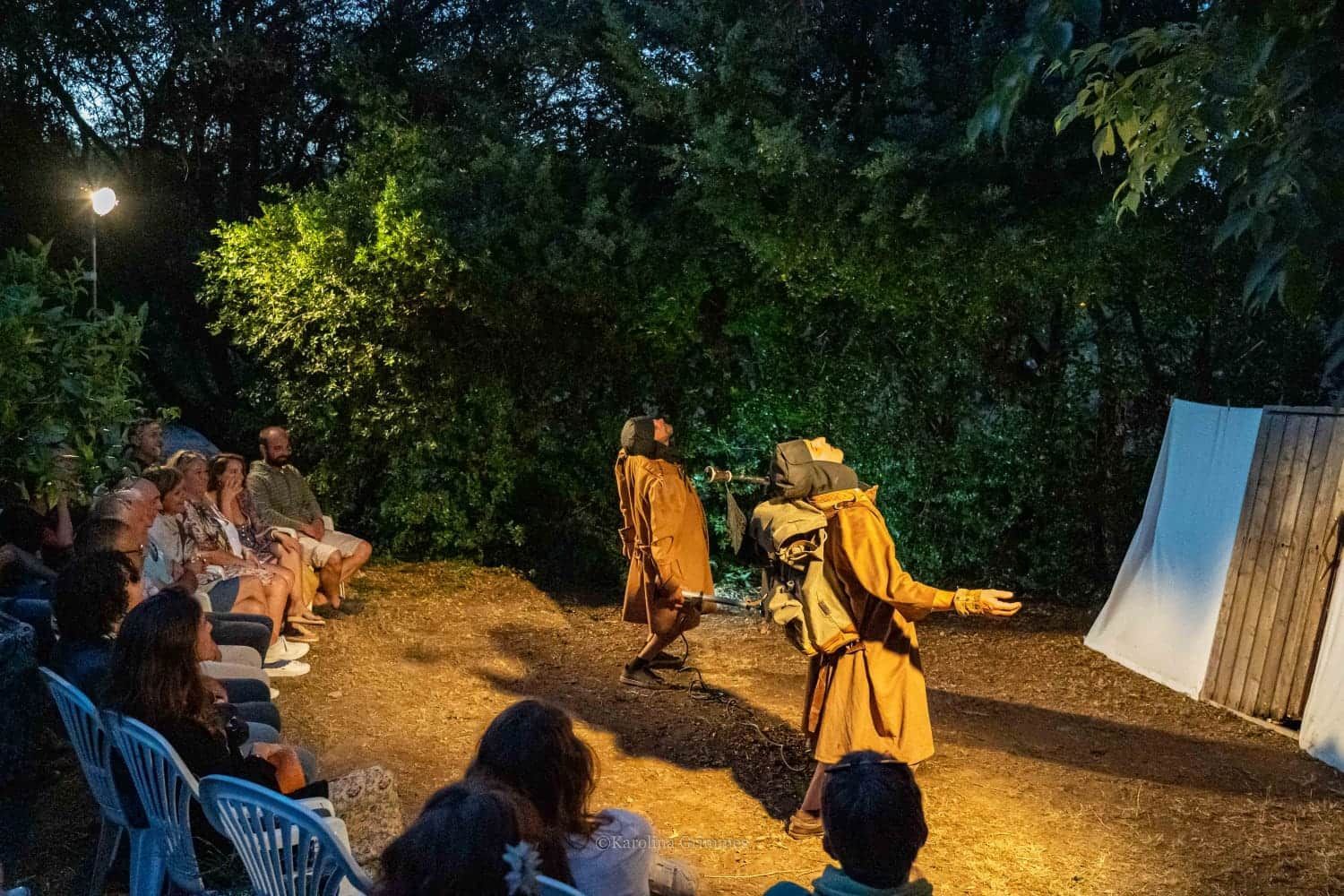 Un grupo de personas están sentadas en sillas viendo una obra de teatro en un escenario.