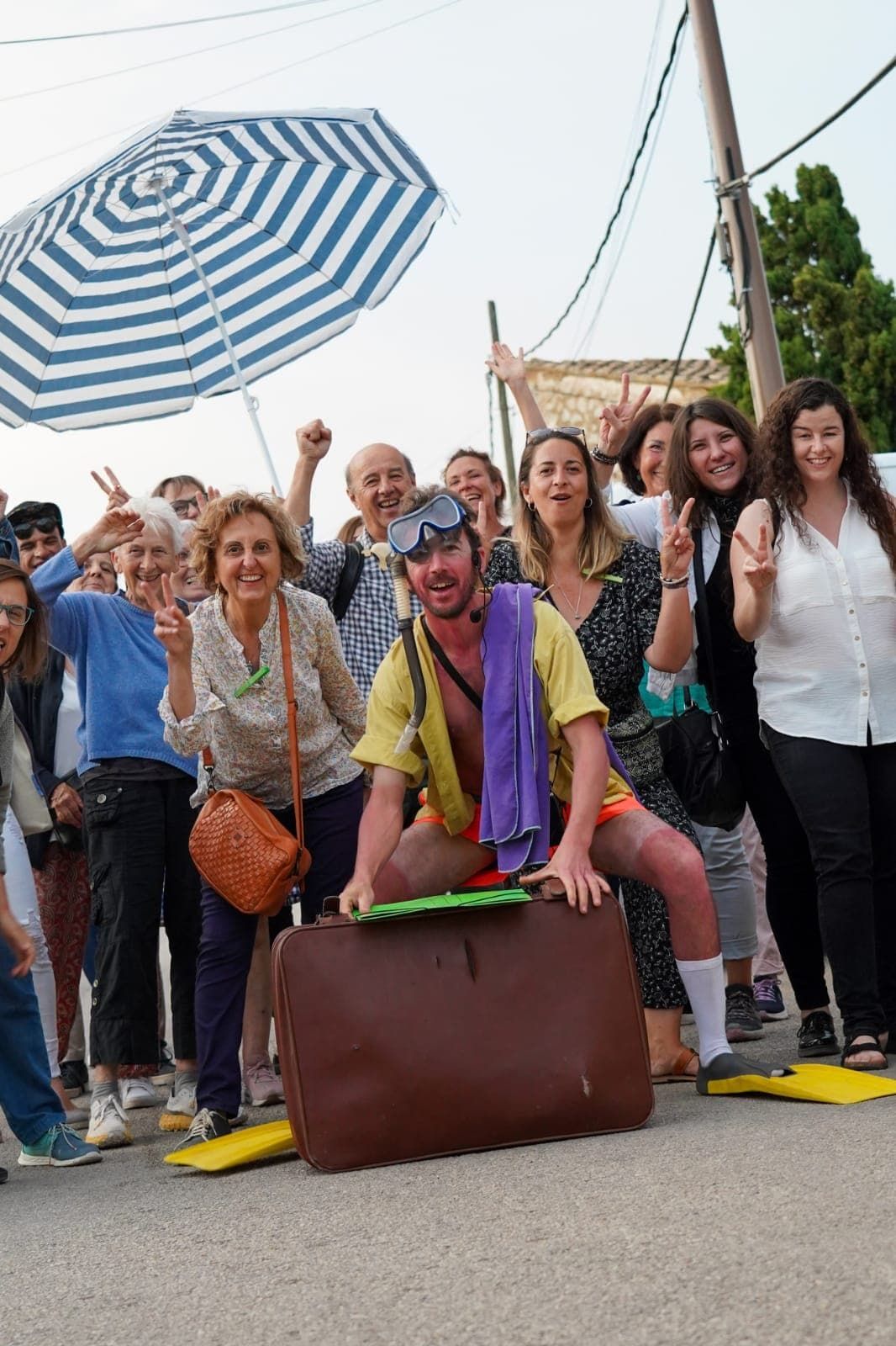Un grupo de personas posa para una foto con un hombre sentado en una maleta.