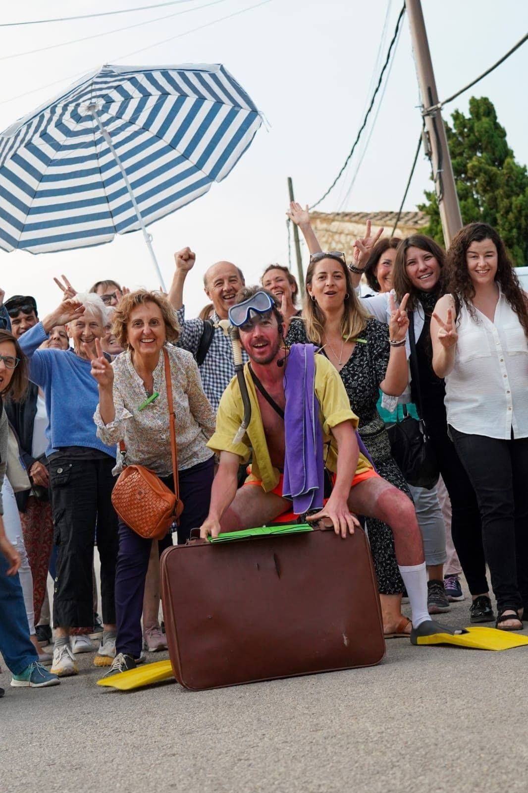 Un grupo de personas posa para una foto con un hombre sentado en una maleta.