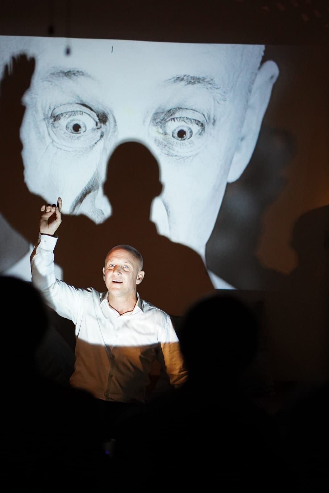 Un hombre está parado frente a una proyección del rostro de un hombre.