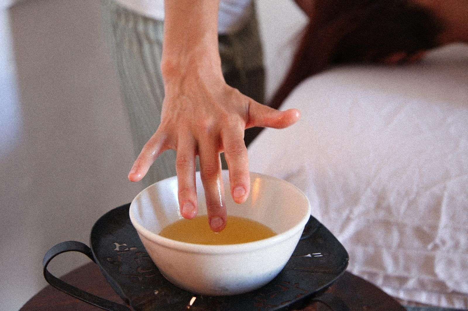 La mano de una persona está metiendo la mano en un recipiente con líquido.