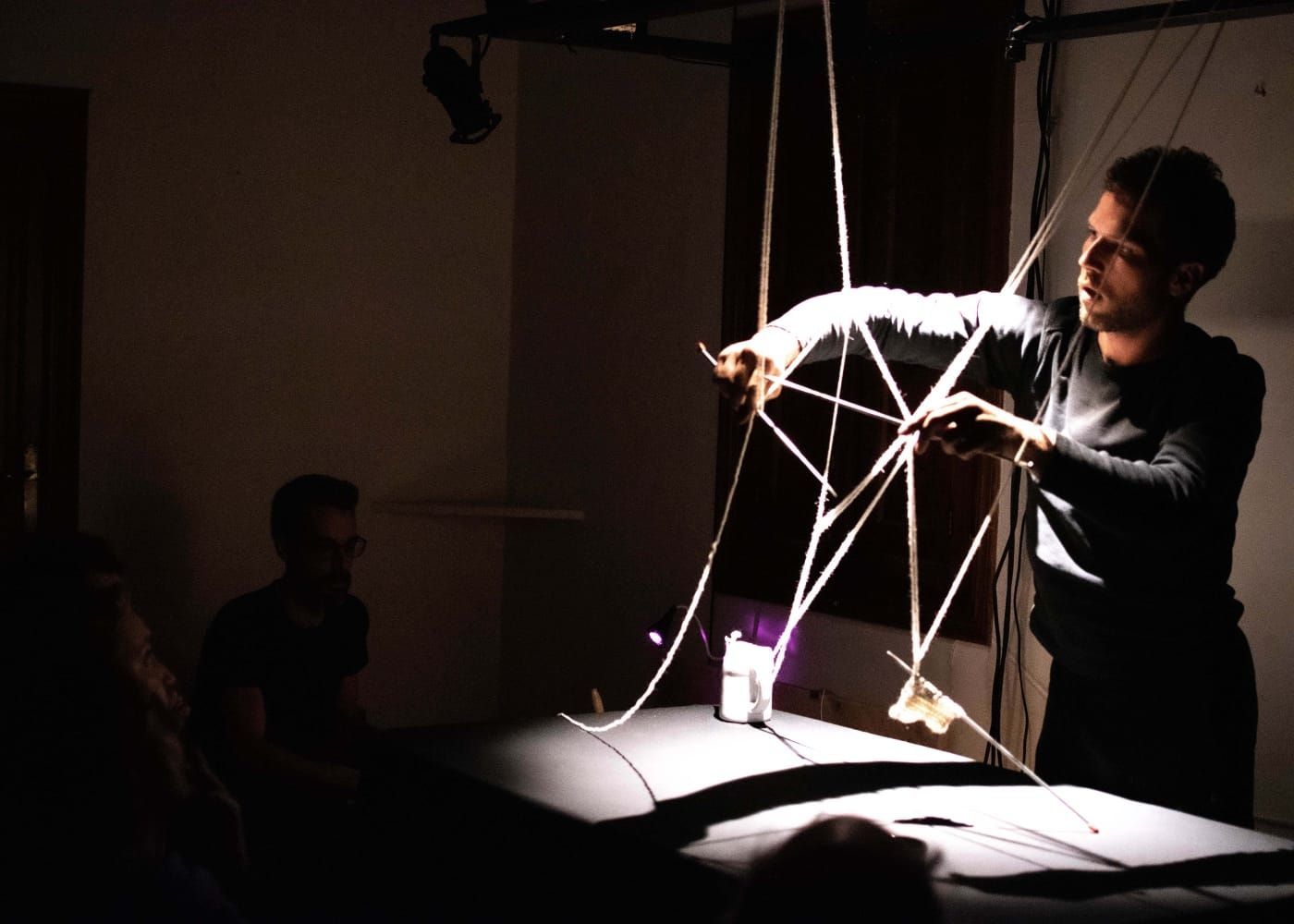 Un hombre sostiene una cuerda en una habitación oscura.